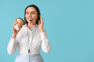 Canvas Print - Female technical support agent in headset with paper cup of coffee on blue background