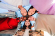 © Jose Calsina - Low angle view of a group of multiracial young friends hugging in a circle, smiling and looking at camera with a positive expression. Team of teenagers laughing and ambrecing each others outside.