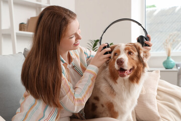 Sticker - Young woman and cute Australian Shepherd dog with headphones listening to music at home