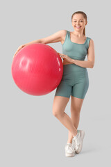 Poster - Sporty young woman with fitball on light background