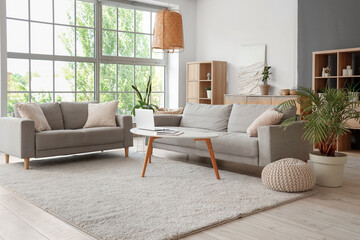 Sticker - Interior of stylish living room with grey sofas and laptop on table