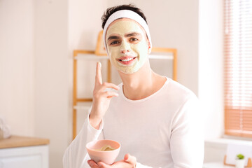 Poster - Young man applying clay mask in bathroom, closeup