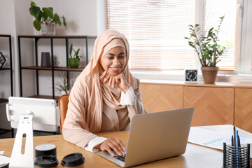 Canvas Print - Muslim businesswoman working with laptop at table in office