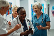 © Watcharakorn - A black female doctor and senior woman with hospital staff using a smartphone in the corridor of a clinic, the group laughing together during a break at the medical office.