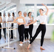 © JackF - Female teacher leading ballet class, showing graceful dance movements for women of different ages standing at barre, emphasizing discipline in studio