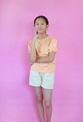 Wall Mural - Funny face Asian girl kid hold finger cheek while standing isolated on pink studio background.