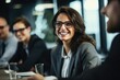 © vefimov - A woman in a business suit is smiling at the camera. She is surrounded by other people, all of whom are also smiling. The atmosphere is friendly and positive