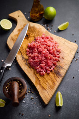 Wall Mural - Sliced and chopped tuna fillet on wooden cutting board at domestic kitchen cooking traditional tartare