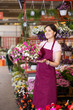 © JackF - Professional female gardener arranging potted Petunia flowers for market and wearing greenhouse uniform