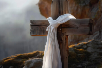 Wall Mural - Wooden cross with white cloth on top of rocky hill at sunset