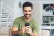 © Daniel Ernst - Laughing latin american man with fashionable beard shopping online with cellphone