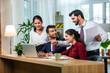 © StockImageFactory - Indian young businesspeople using laptop in group meeting at desk