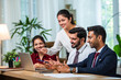 © StockImageFactory - Indian young businesspeople using laptop in group meeting at desk