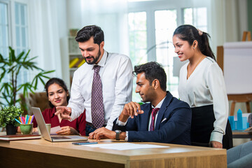 Wall Mural - Indian young businesspeople using laptop in group meeting at desk