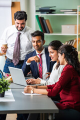 Wall Mural - Indian young businesspeople using laptop in group meeting at desk