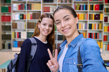 Selfie portrait of two girls high school students looking at camera inside classroom