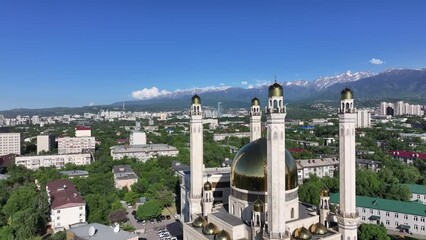 Wall Mural - A mosque in the Kazakh city of Almaty against the backdrop of a mountain range on a spring day