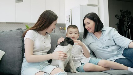 an asian family of mother son and daughter spends time together sitting on the couch with their cute