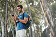 © peopleimages.com - Man, hiking and smile with smartphone in forest for browsing internet, networking and social media. Fitness, survival and workout in woods on countryside with texting, message and chat on app