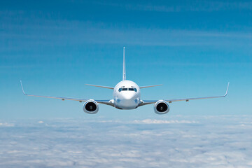 Front view of the white passenger airliner flying in the air above the clouds