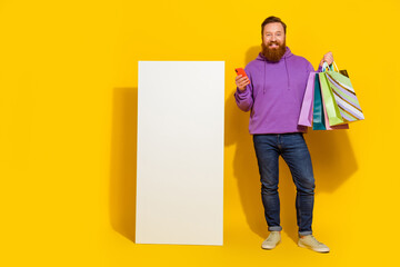 Wall Mural - Full size portrait of cheerful nice man hold telephone packages empty space ui menu panel isolated on yellow color background