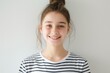© World of AI - smiling young girl with her hair in a bun, wearing a striped t-shirt, studio setting with a plain white background