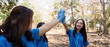 © Natee Meepian - Female volunteer high fiving in forest. Concept of teamwork, unity, and environmental service