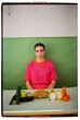 © VISTA by Westend61 - Fashionable woman sitting with food at table in front of wall