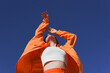 © VISTA by Westend61 - Woman in orange casuals dancing with arms raised under clear blue sky on sunny day