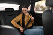 © New Africa - Woman fastening safety seat belt inside modern car