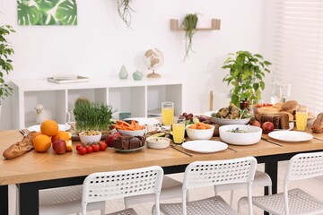 Wall Mural - Healthy vegetarian food, glasses of juice, cutlery and plates on wooden table indoors