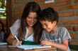 © zakiroff - Woman with long hair helps child with homework at a table with brick background