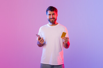 Poster - A man is holding a card in one hand and a cell phone in the other. He appears to be focusing on the phone screen while holding the card. The background is neutral and nondescript.