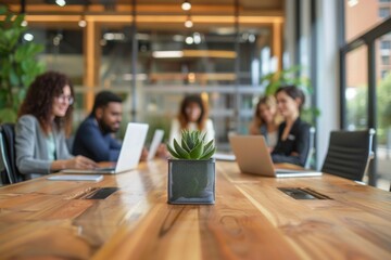 Poster - A group of professionals sit around a wooden table in an office environment with laptops