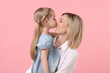 © New Africa - Daughter kissing her happy mother on pink background