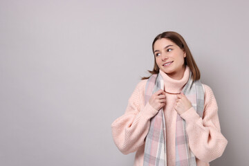 Wall Mural - Beautiful woman in warm scarf on gray background, space for text