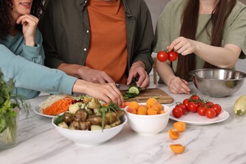 Wall Mural - Friends cooking healthy vegetarian meal at white marble table in kitchen, closeup