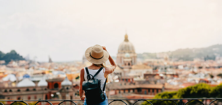 Young attractive smiling girl tourist exploring new city at summer