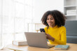 © ArLawKa - Happy young woman using laptop sitting at desk writing notes while watching webinar. Study online. Look at web learning or have online meeting, distance learning concept.