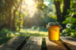 © Ivan - A jar of clear homemade honey on a wooden table with a beautiful sunset in the background and green trees or an orchard in the background, unlabeled with space for text or name and logo
