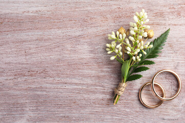 Wall Mural - Small stylish boutonniere and rings on light wooden table, top view. Space for text