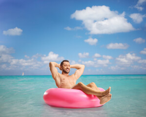 Wall Mural - Handsome young man in the sea enjoying in a swimming ring