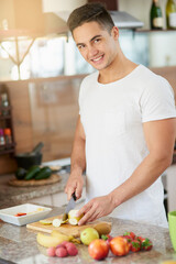 Wall Mural - Man, portrait and cooking a fruit salad for breakfast in kitchen with cutting apple, healthy meal and nutrition in home. Person, wellness and preparation of organic brunch for detox and vegan diet