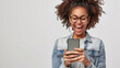 © mittpro - A cheerful woman model in casual attire, holding a smartphone, looking at the screen with an excited expression