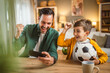 © Miljan Živković - Father and son watch football match on mobile phone and cheer at home