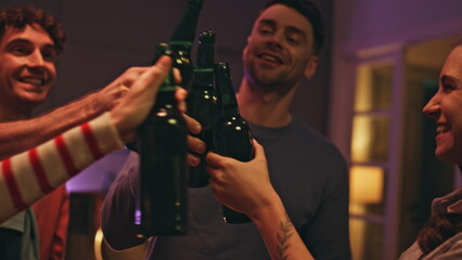 Partying people drinking beer at night hangout at home closeup. Friends clinking