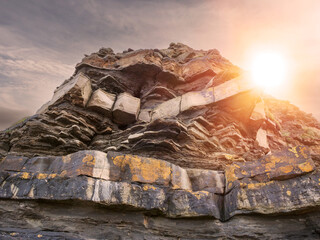 Wall Mural - A rocky hillside with a sun shining on it. The sun is in the sky and the hill is covered in rocks. West coast of Ireland. Rough stone terrain.