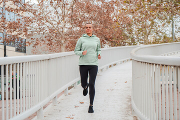 Mid adult woman running at morning enjoying her fitness workout. Short hair female jogging during her cardio and resistance training. Powerful caucasian lady enjoying the sport with vitality