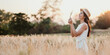 © Satori Studio - A woman is standing in a field of tall grass, holding a flower in her hand. The scene is peaceful and serene, with the sun shining down on the woman and the grass