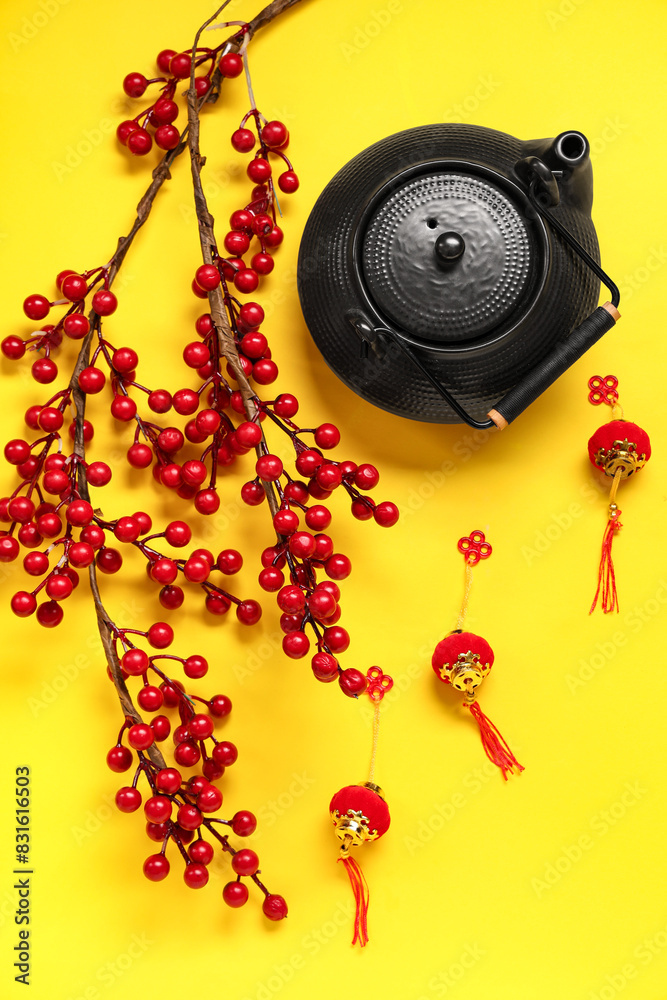 Teapot with berries and Chinese symbols on yellow background. New Year celebration